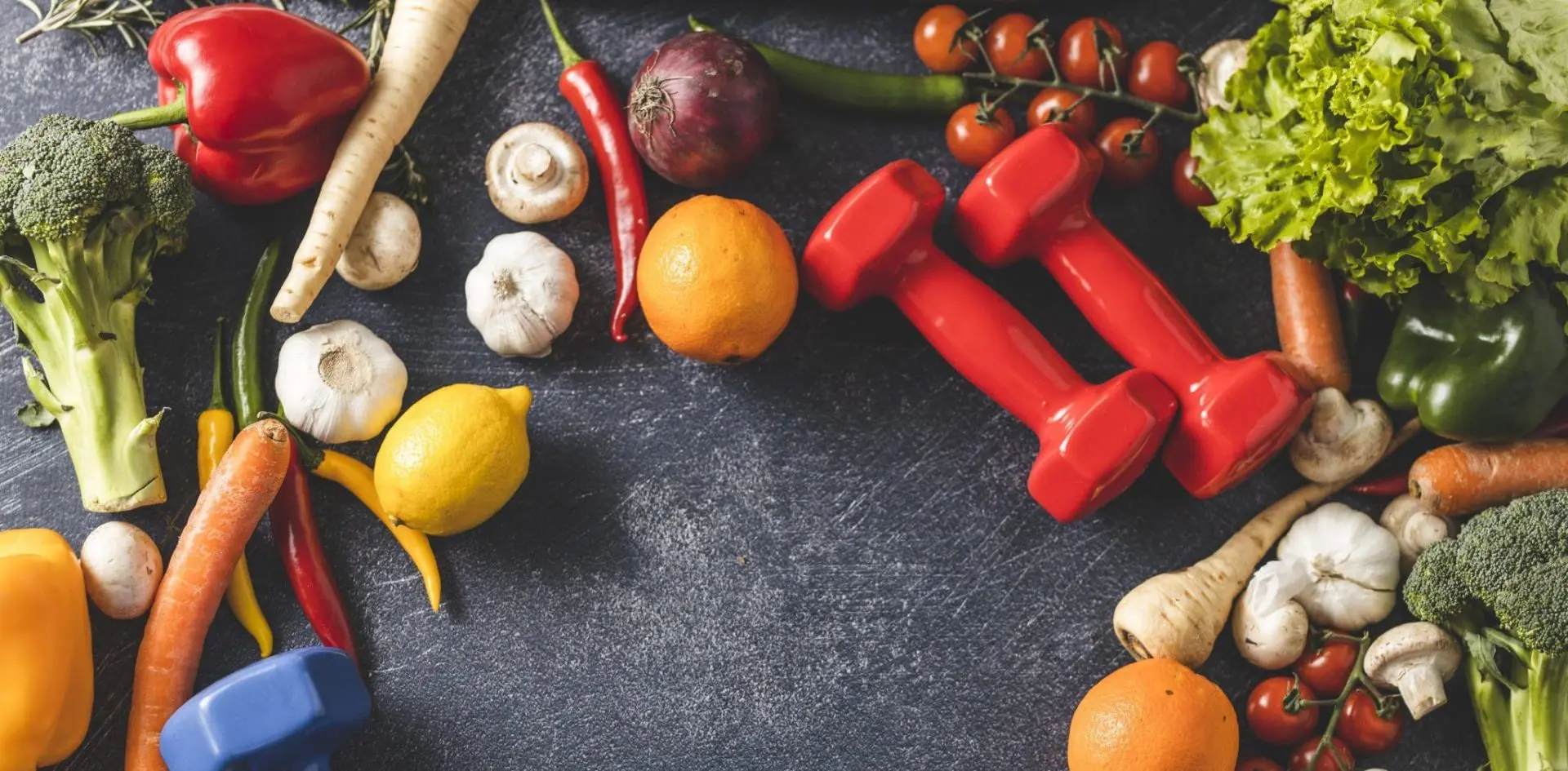 Overhead photo of fruits, vegetables, and hand weights on table