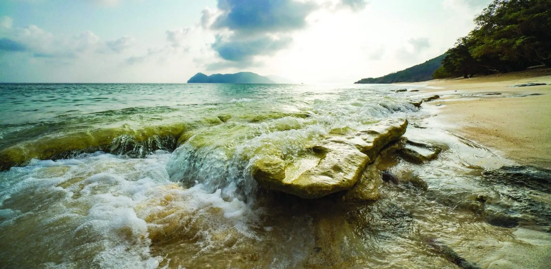 Photo of ocean wave washing over island beach